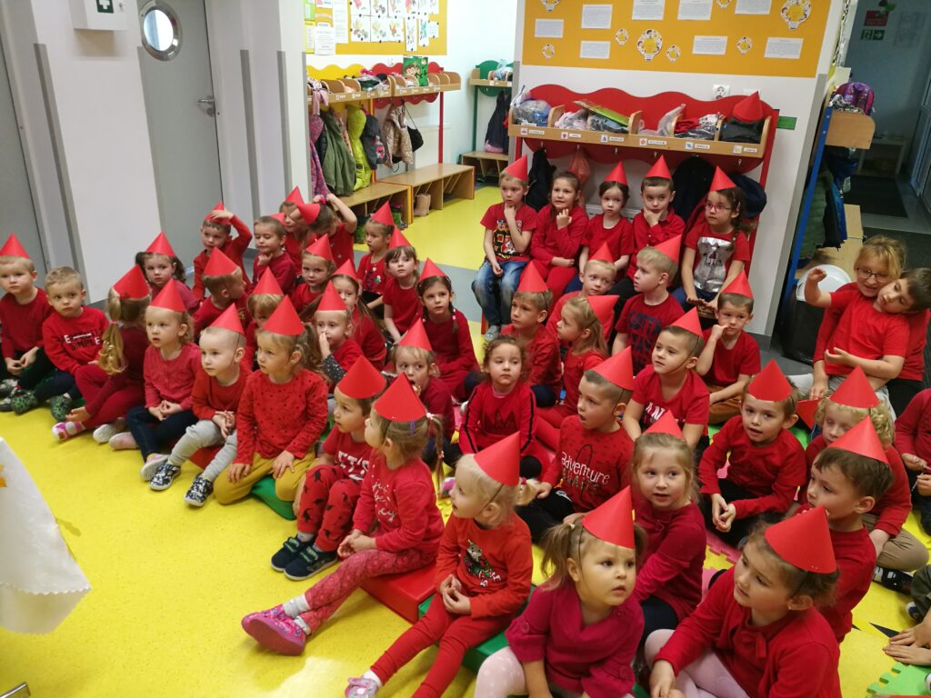 grupa dzieci ubranych na czerwono, z czerwonymi czapeczkami na głowie