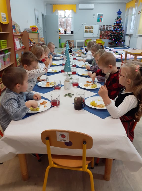 W grupie maluchy odbył się Świąteczny Obiad. Wszystkie dzieci ubrane są w odświętne ubrania . siedzą przy jednym wspólnym stole. 