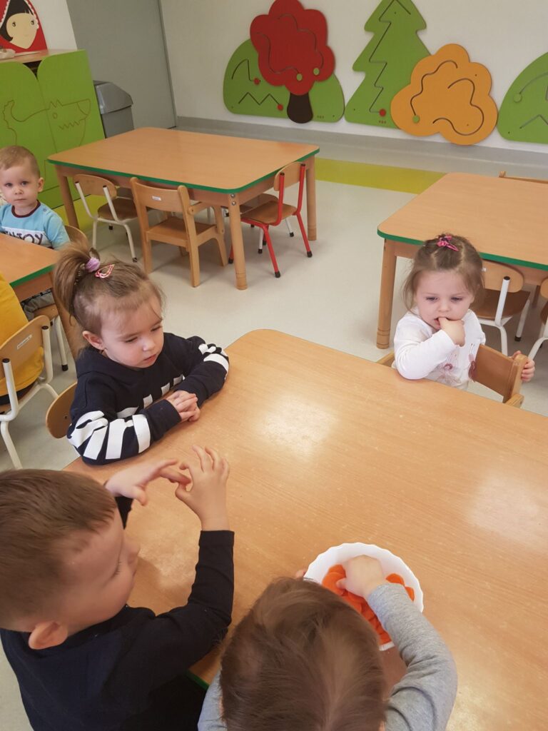 Dzieci z grupy Krasnali jedzą marchewkowe chipsy.