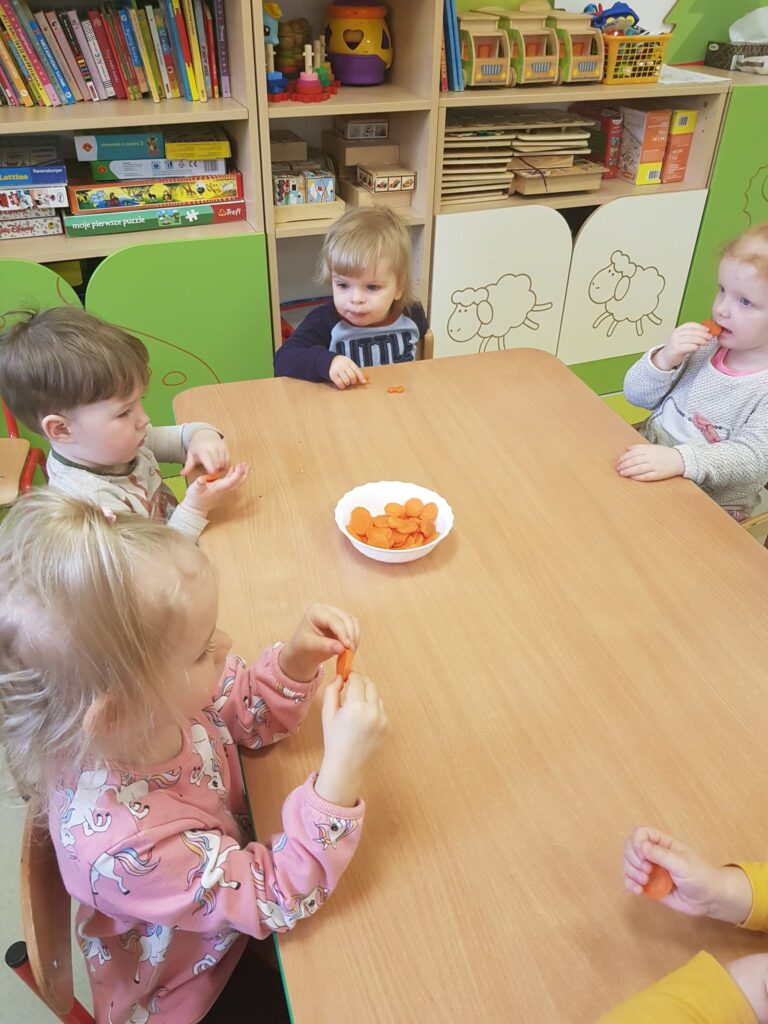 Dzieci z grupy Krasnali jedzą marchewkowe chipsy.