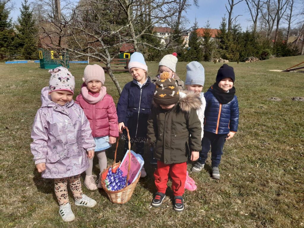 Dzieci pozują do zdjęcia z koszykiem pełnym niespodzianek od zajączka.