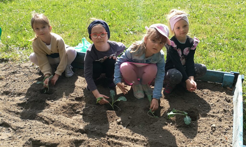 cztery dziewczynki sadzą rośliny w ogrodzie