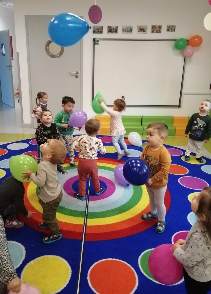 grupa dzieci bawią się kolorowymi balonami 