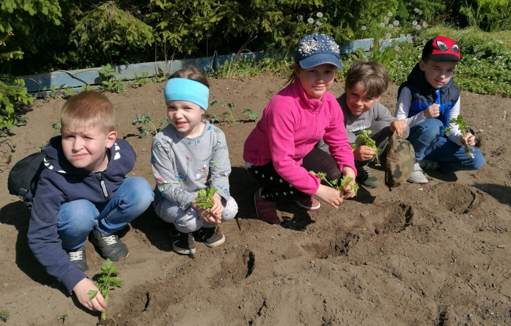 chłopcy i dziewczynki sadzą rośliny w ogrodzie