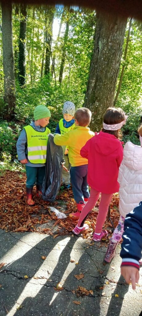 dzieci wspólnie zbierają śmieci w parku