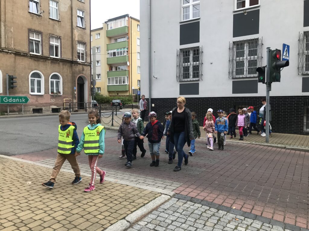 Dzieci przedszkolne sa uczestnikami ruchu drogowgo, Wspólnie z pania przechodza przez pasy przy świetle zielonym. W praktyce dokonala zasady bezpiecznego poruszania sie przez jezdnię