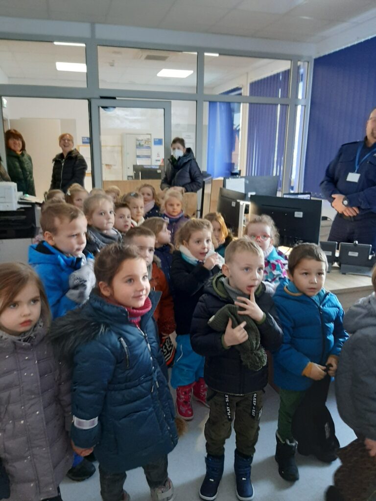 Dzieci wraz z paniami i panem policjantem znajdują się w dyżurce Komendy Policji w Sławnie.