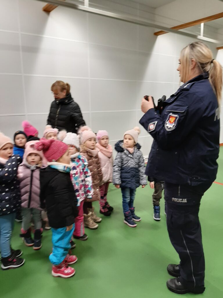 Pani policjantka pokazuje dzieciom broń treningową.