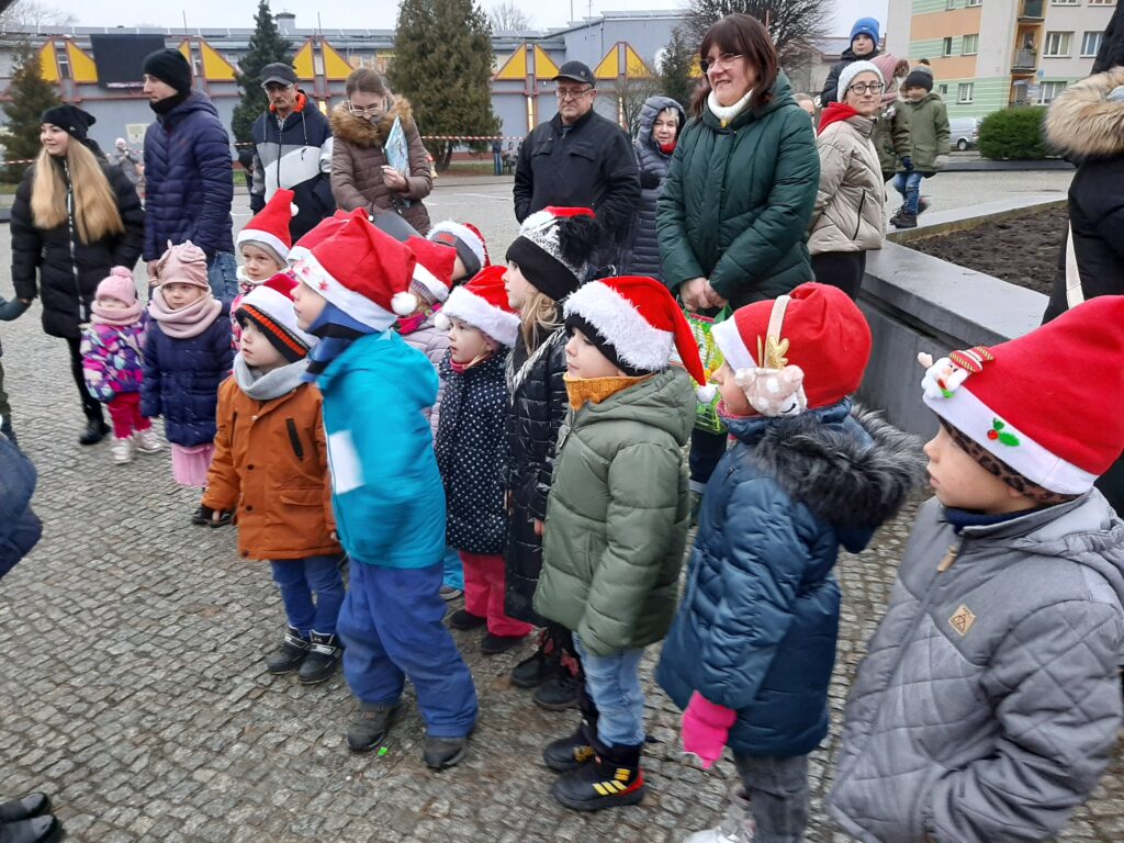 Dzieci z grupy Średniaki, wraz z innymi mieszkańcami miasta oczekują na placu miejskim na uroczyste zapalenie światełek na choince.