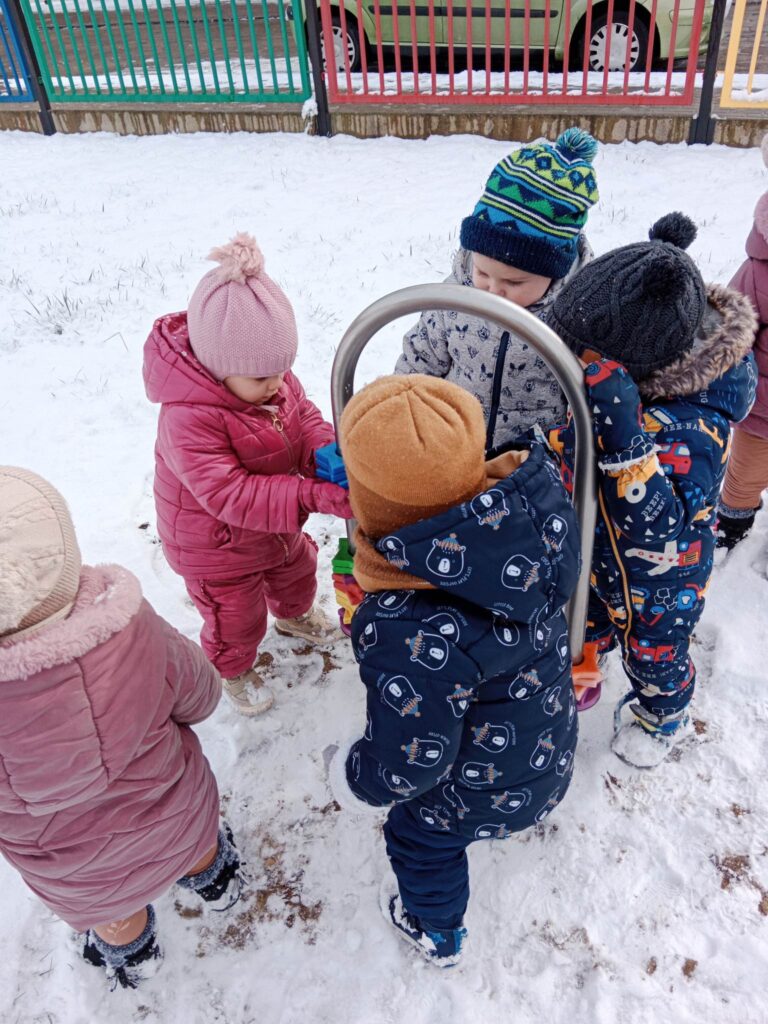 Dzieci z grupy Muchomorków bawią się na śniegu.