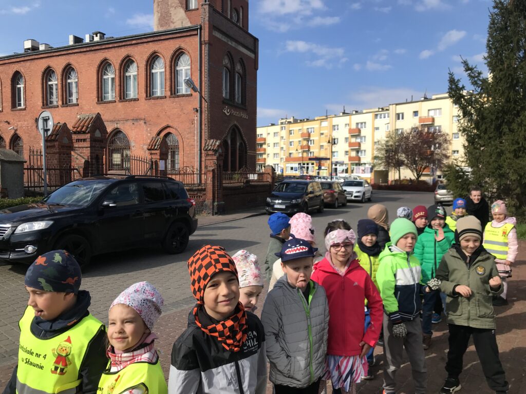 Starszaki stoją obok budynku poczty.Zwiedzaja swoje miasto 