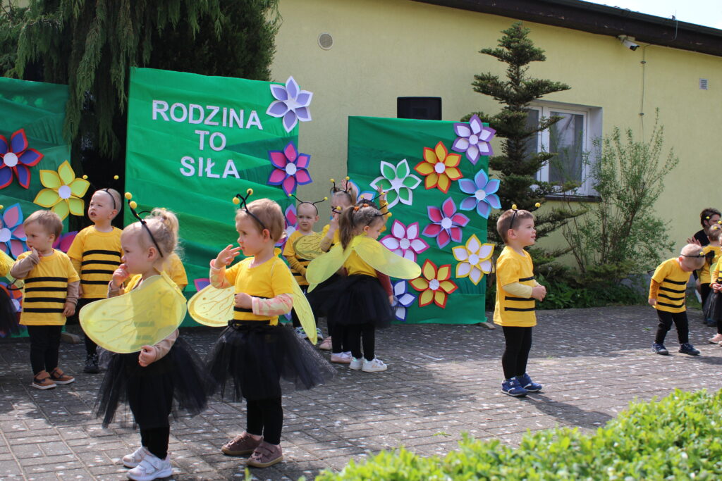 Dzieci w przebraniu pszczółek tańczą w takt muzyki.