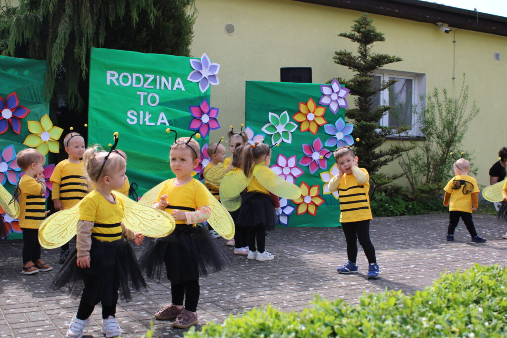 Dzieci w przebraniu pszczółek tańczą w takt muzyki.