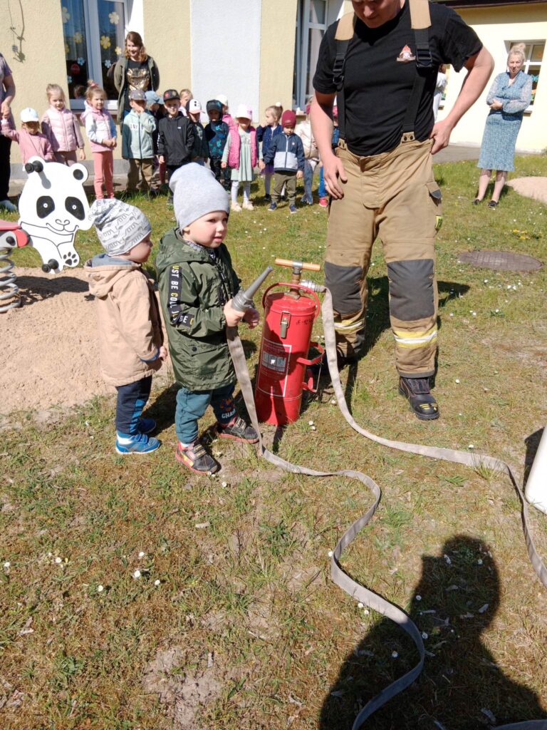 dzieci na placu zabawa używają sikawki strażackiej 