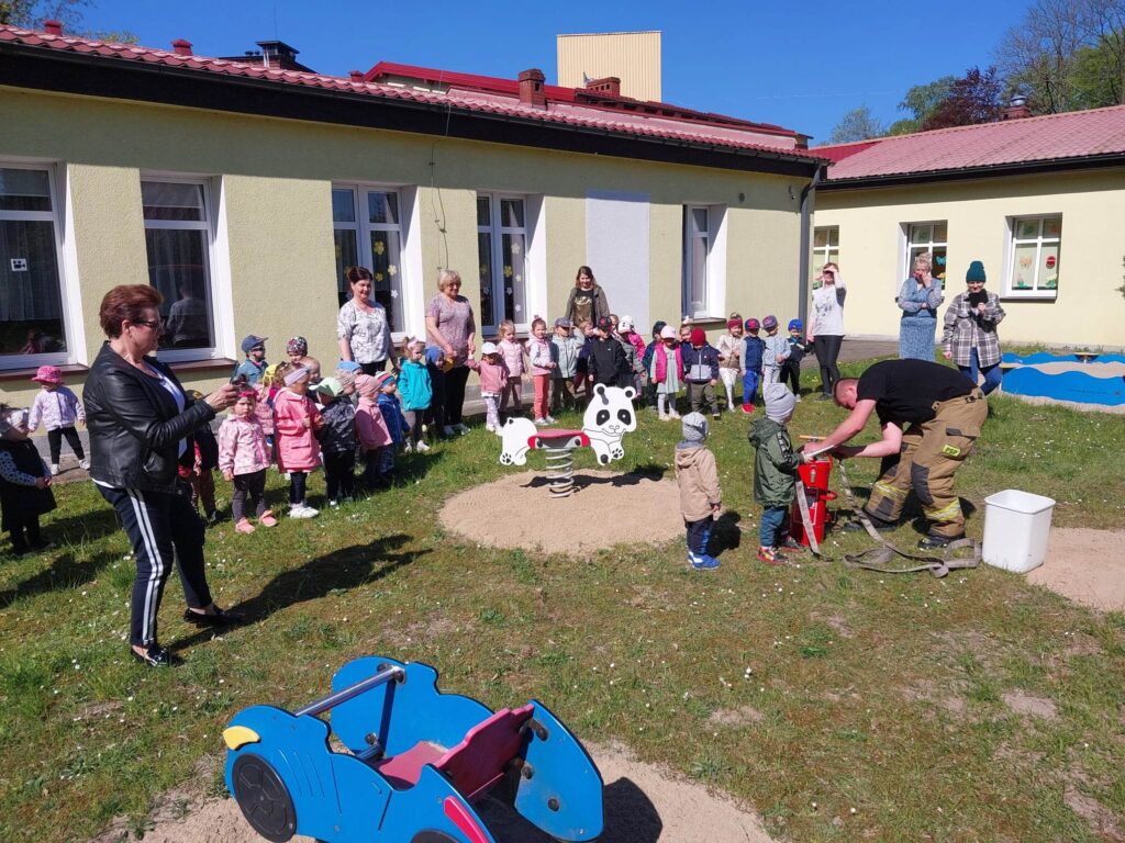 dzieci na placu zabawa obserwują strażaka 