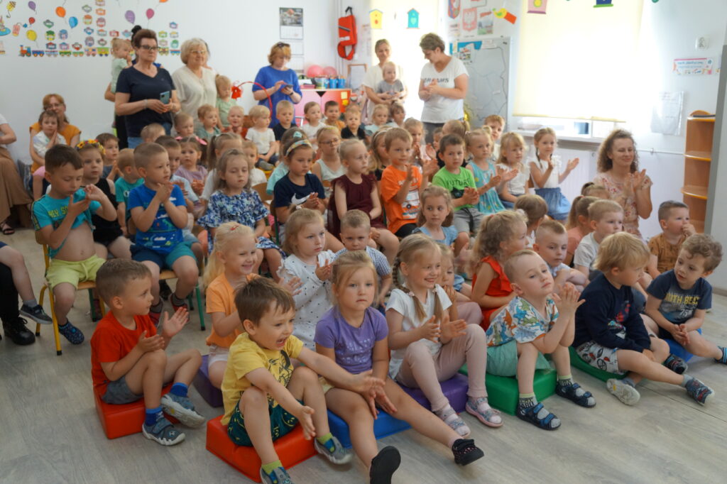 Dzieci ze zlobka i przedszkola oglądaja ostatni występ starszaków na uroczuystym ich pożegnaniu