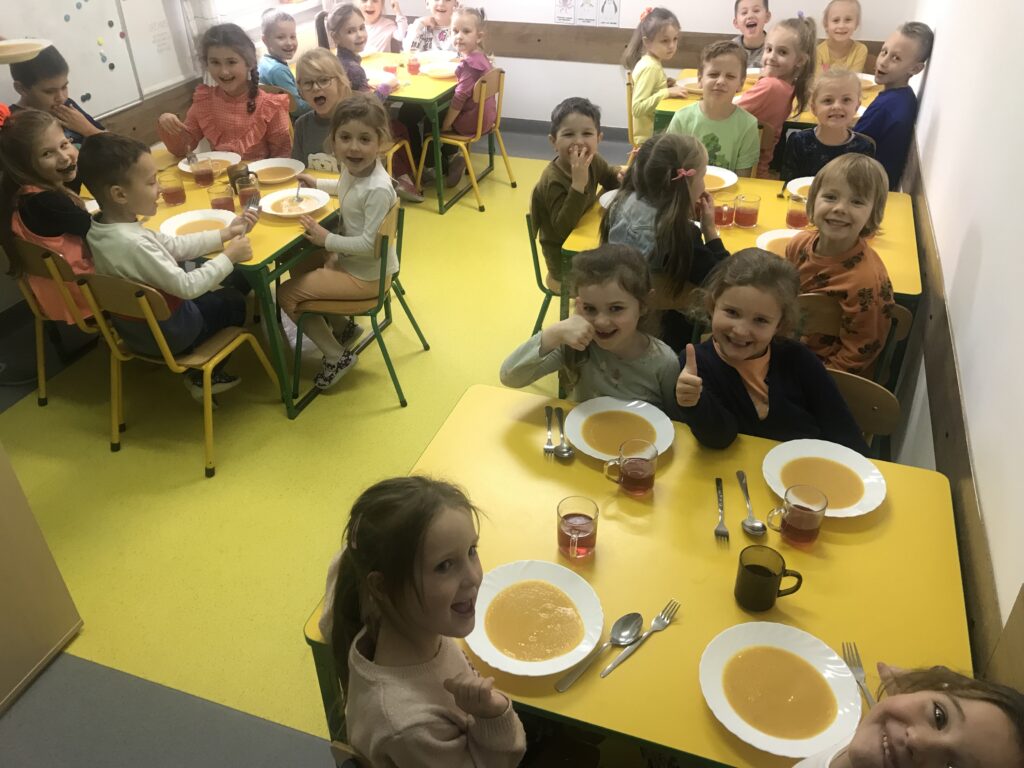 dzieci siedza w przedszkolnej stołówce, degustują zupę dyniową ugotowana specjalnie z okazji ŚWIĘTA DYNI 