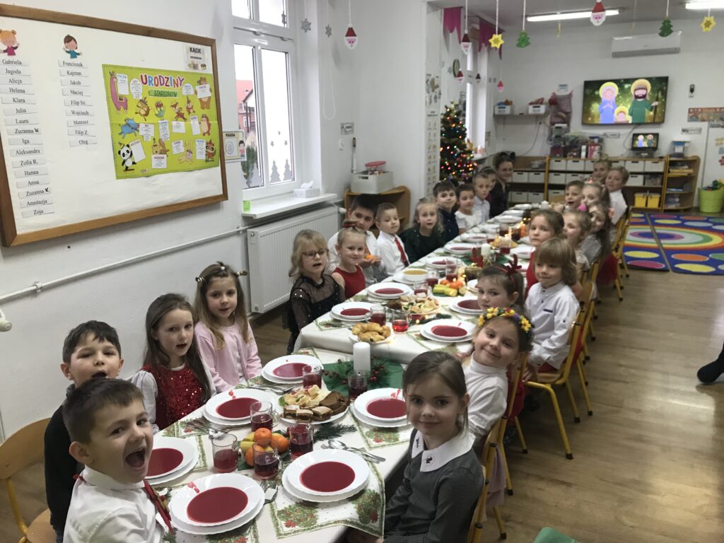 Dzieci z najstarszej grupy siedza przy świątecznym posiłku. Jedza razem na swojej sali przy uroczyście udekorowanym stole