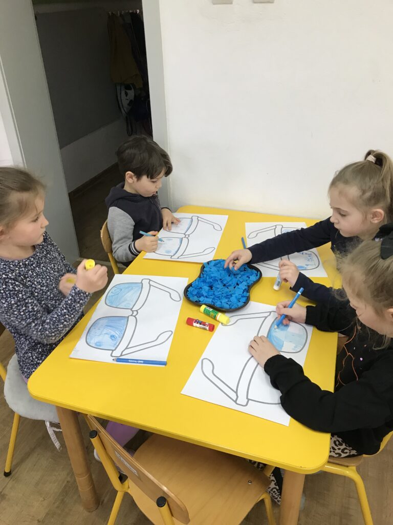Dzieci na zajęciach ryzuja pracę niebieska kredka z okazji obchodów Dnia Autyzmu