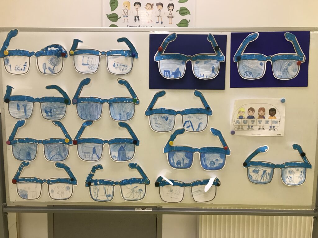 Prace dzieci w formie okularów wisza na wystawie. Prezentują swiat widziany oczami autysty. 