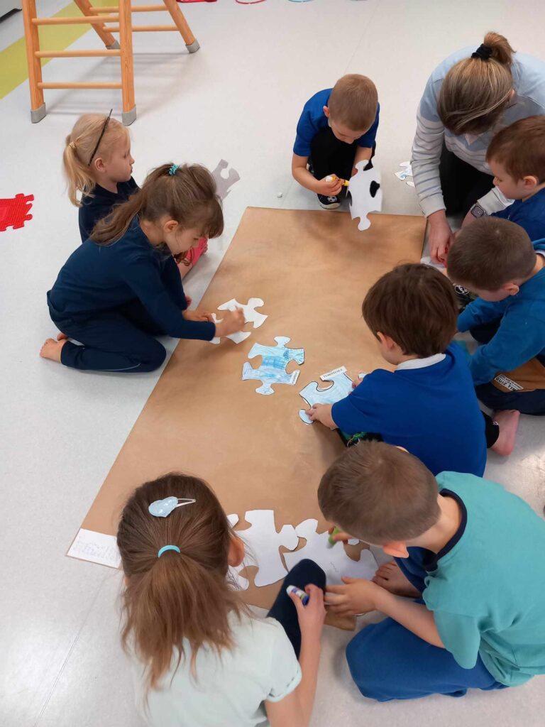 Praca zespołowa dzieci - przyklejanie puzzli