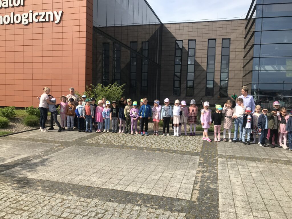 Dzieci przedszkolne stoją przed budynkiem w mieście Słupsk, oczekując na przedstawienie muzyczne, które odbędzie się w auli Inkbatora. 