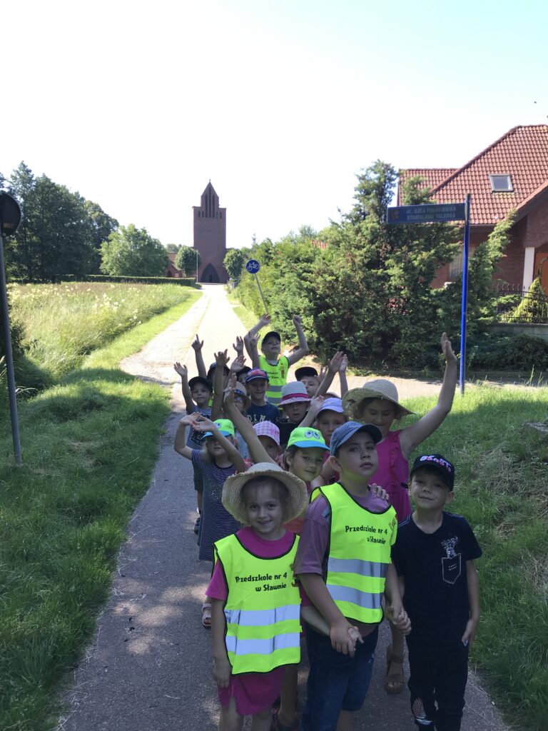 Starszaki spacerując w miście Sławnie oglądaja zabytki - teraz stoją przed małym Kościółkiem