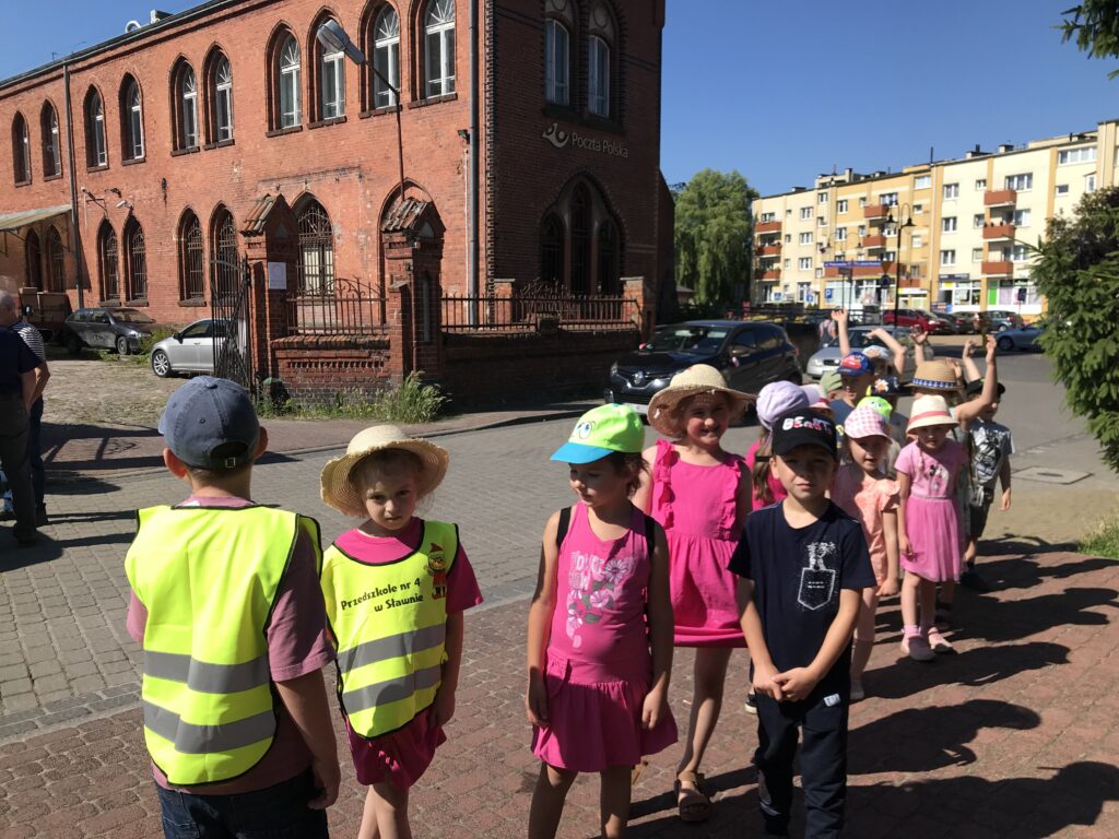 Przy budynku Poczty- dzieci spaceruja ulicami miasta, oglądają stare budynki.