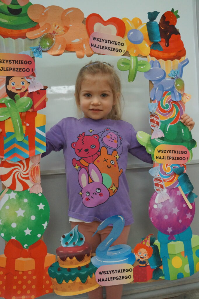 Dziewczynka pozuje w urodzinowej ramce do zdjęć