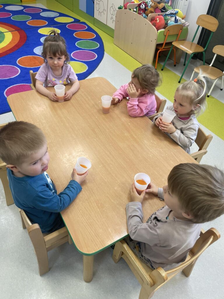 Dzieci degustują sok marchewkowy.