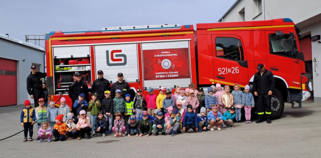 Dzieci pozują na tle wozu strażackiego.