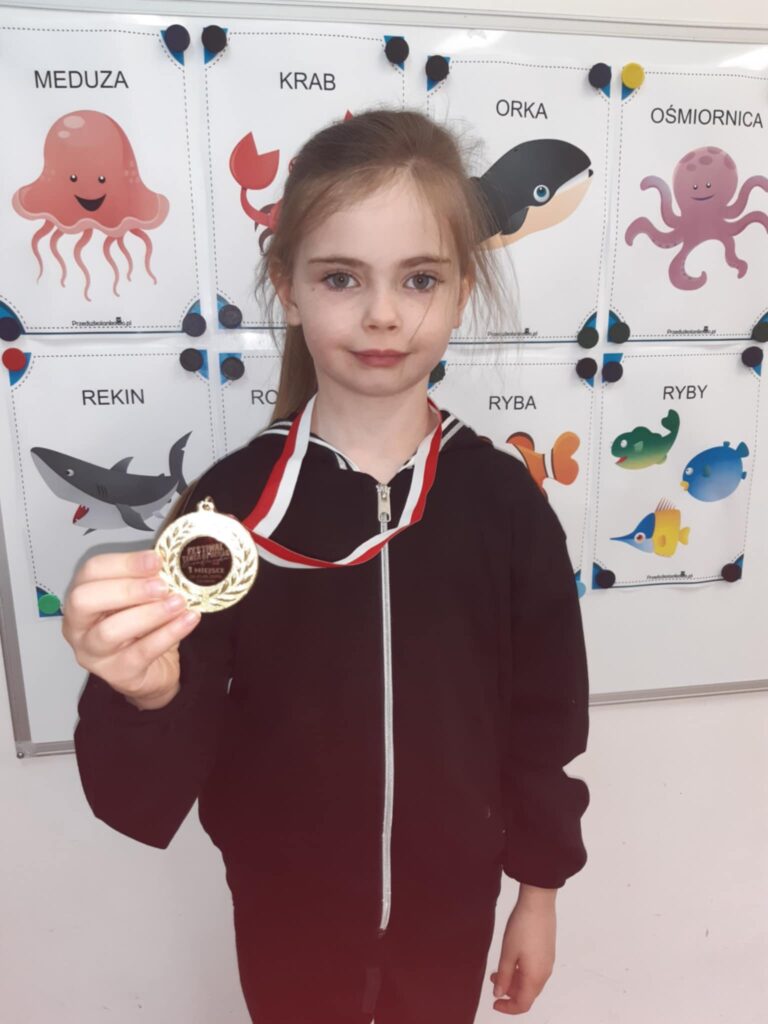 Dziewczynka prezentuje zdobyty medal.