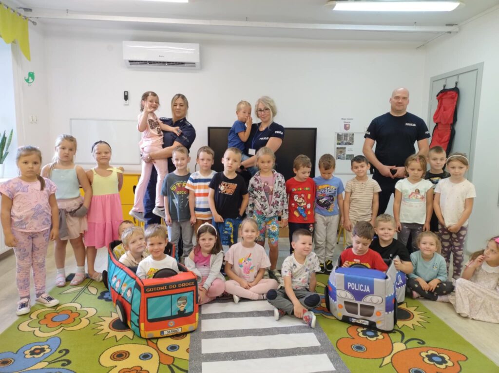 Grupa dzieci pozuje z policjantami do wspólnego zdjęcia.