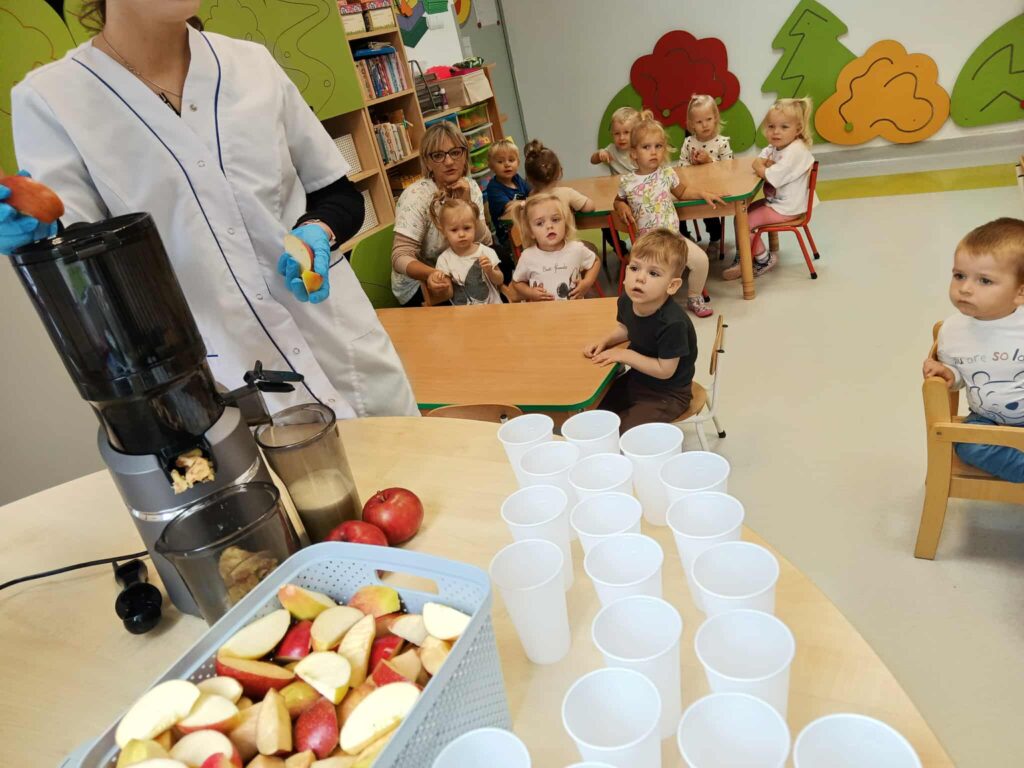 DZIECI OBSERWUJĄ PROCES WYCISKANIA SOKU Z JABŁEK