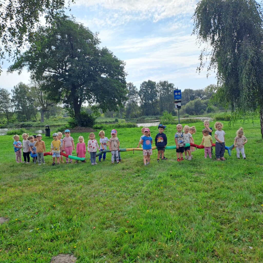 DZIECI STOJĄ PRZY WĘŻU NA TLE STAWKU