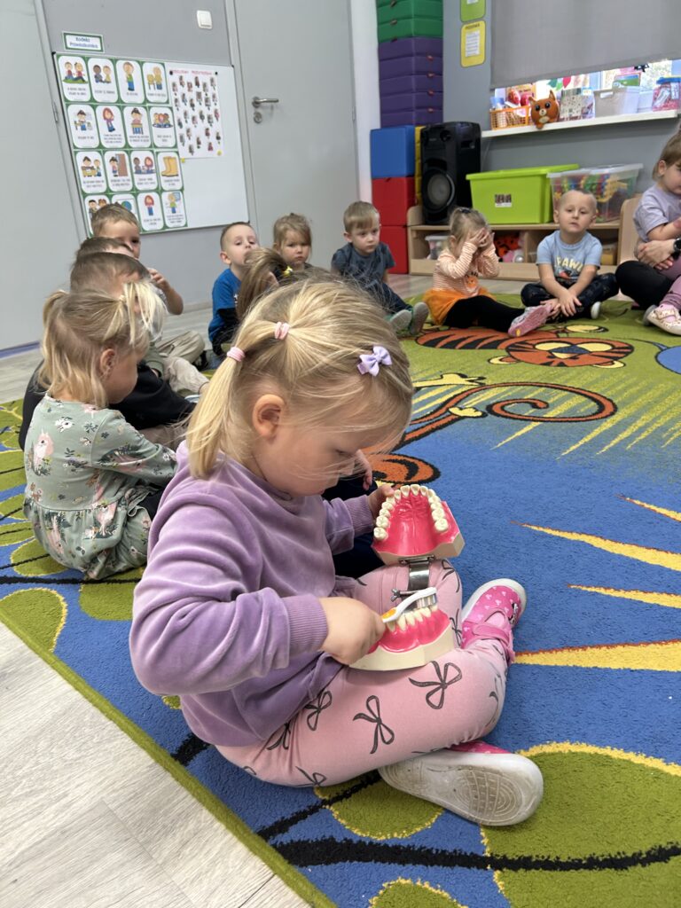 Dziewczynka na modelu próbuje prawidłowo myć zęby.