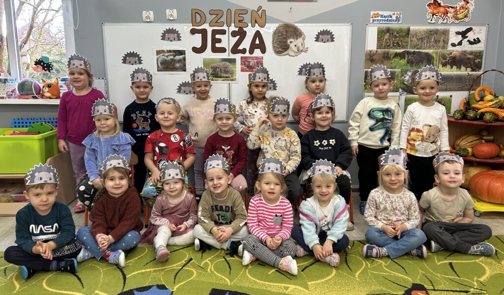 dzieci siedzą przed tablica tematyczną związaną z dniem jeża, na głowach mają tematyczne opaski. W czasie zajęć i zabaw poznawac będą zwyczaje jezy i ich przygotowania do zimy. 