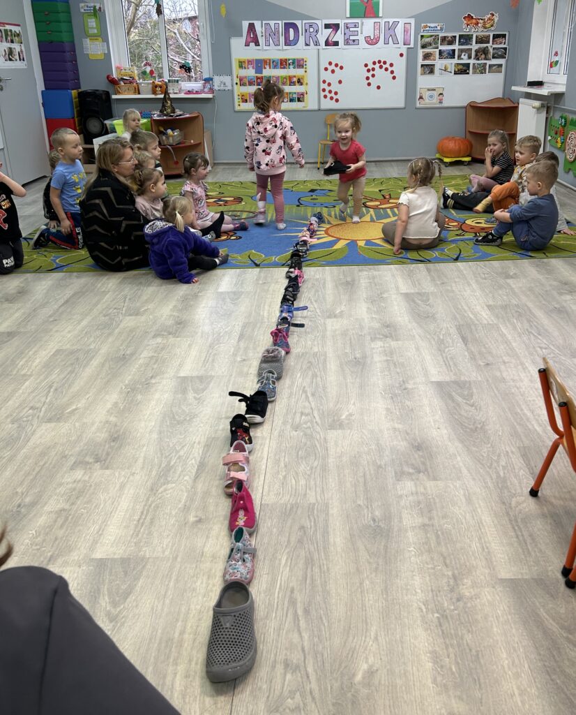 dzieci razem z opiekunami przeprowadzają wróżbę z kapciami-Kto przejdzie przez próg zostaje KROLEM albo KRÓLOWĄ andrzejek