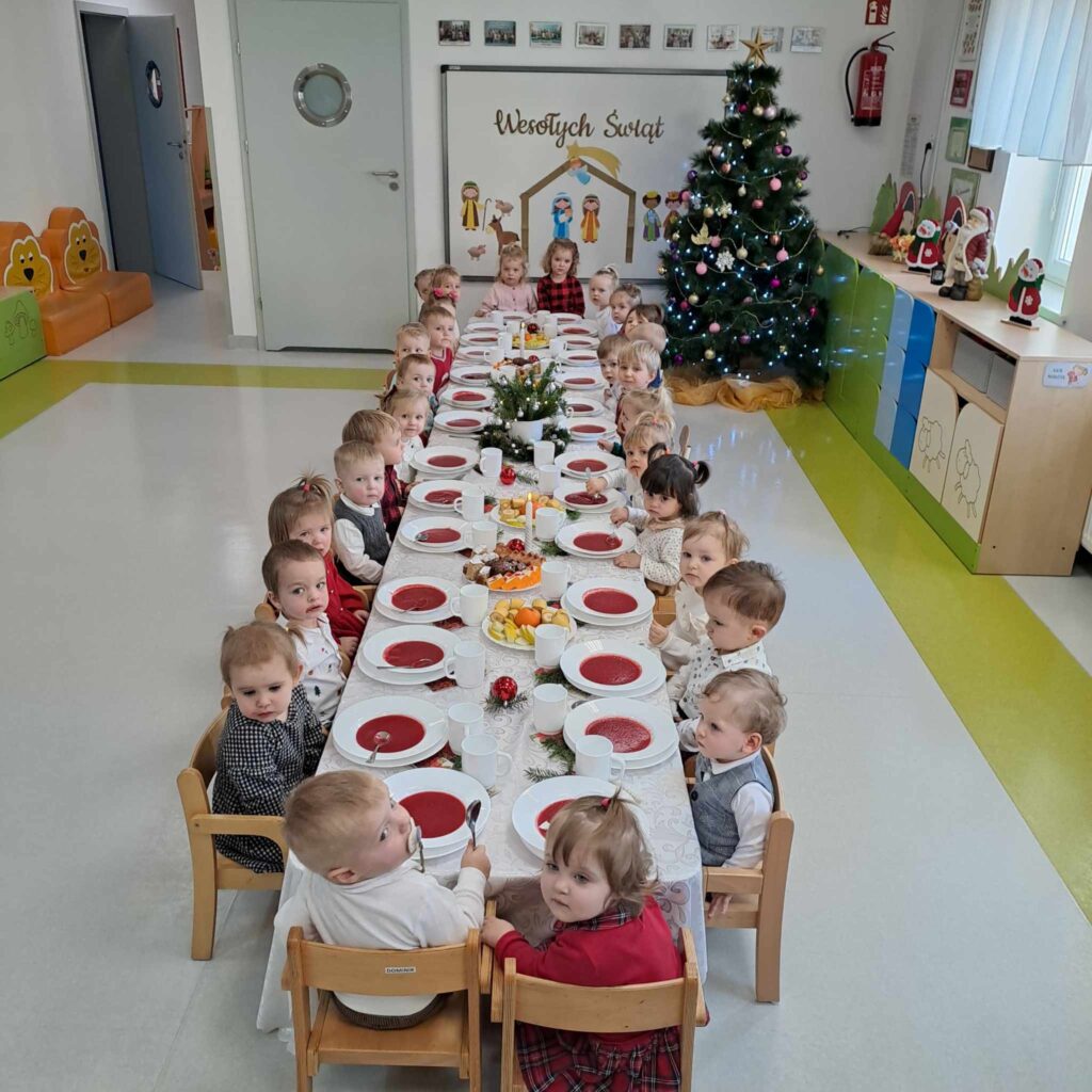 DZIECI JEDZĄ ŚWIĄTECZNY POSIŁEK PRZY WSPÓLNYM STOLE