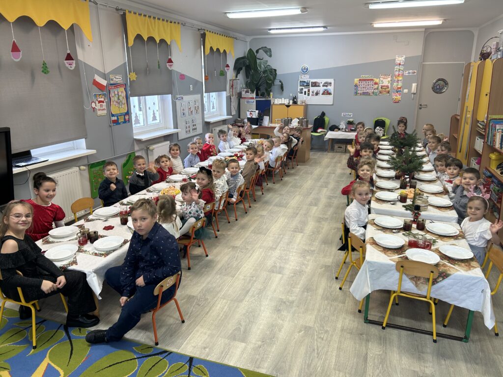 Uroczysty obiad naszych przedszkolaków. Dzieci siedzą przy udekorowanych stołach razem z grupą starszych kolegów i koleżanek