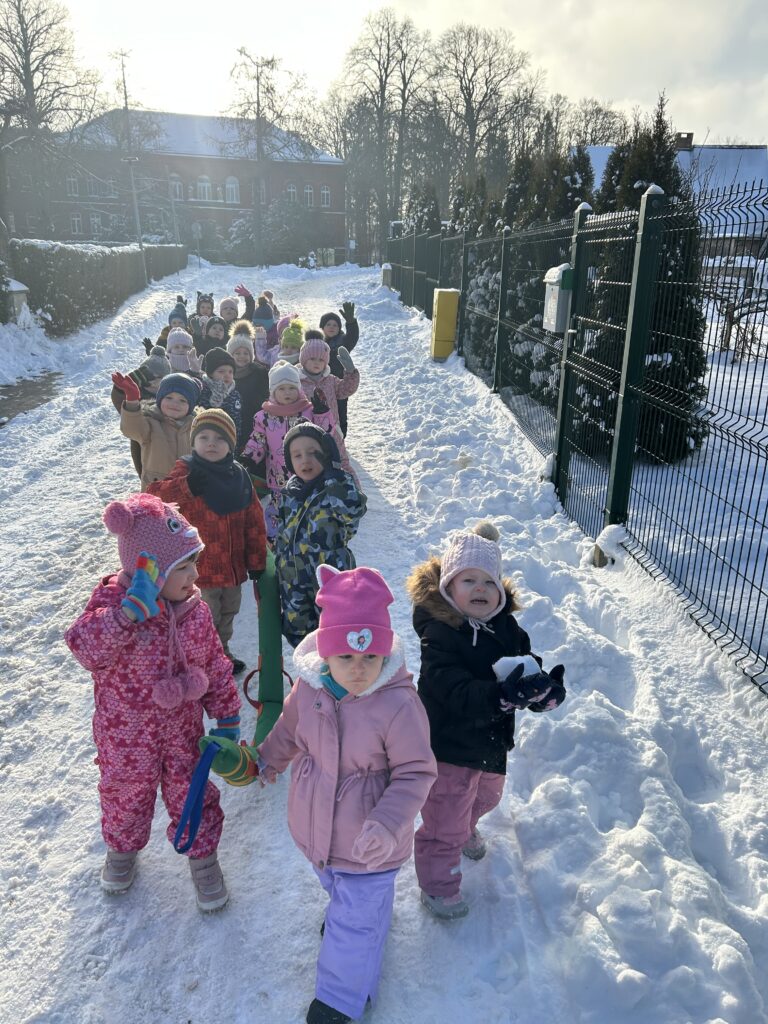 Grupa dzieci z przedszkola spaceruje alejką parkową obserwując piękno zimowych drzew. Dzieci ida z zaprzyjaźnionym wężem, który dba o ich bezpieczeństwo. Po spacerze planuja wykonac pracę plastyczną.