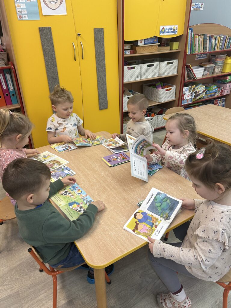 Przedszkolaki w czasie dowolnych zabaw oglądają i opowiadają sobie historyjki z ulubionych książeczek. 