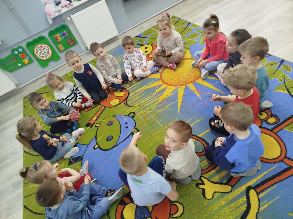 Przedszkolaki przy wykorzystaniu kolorowej wełny buduja swoją sieć połączeń- poznają zasadę przepływu informacji 