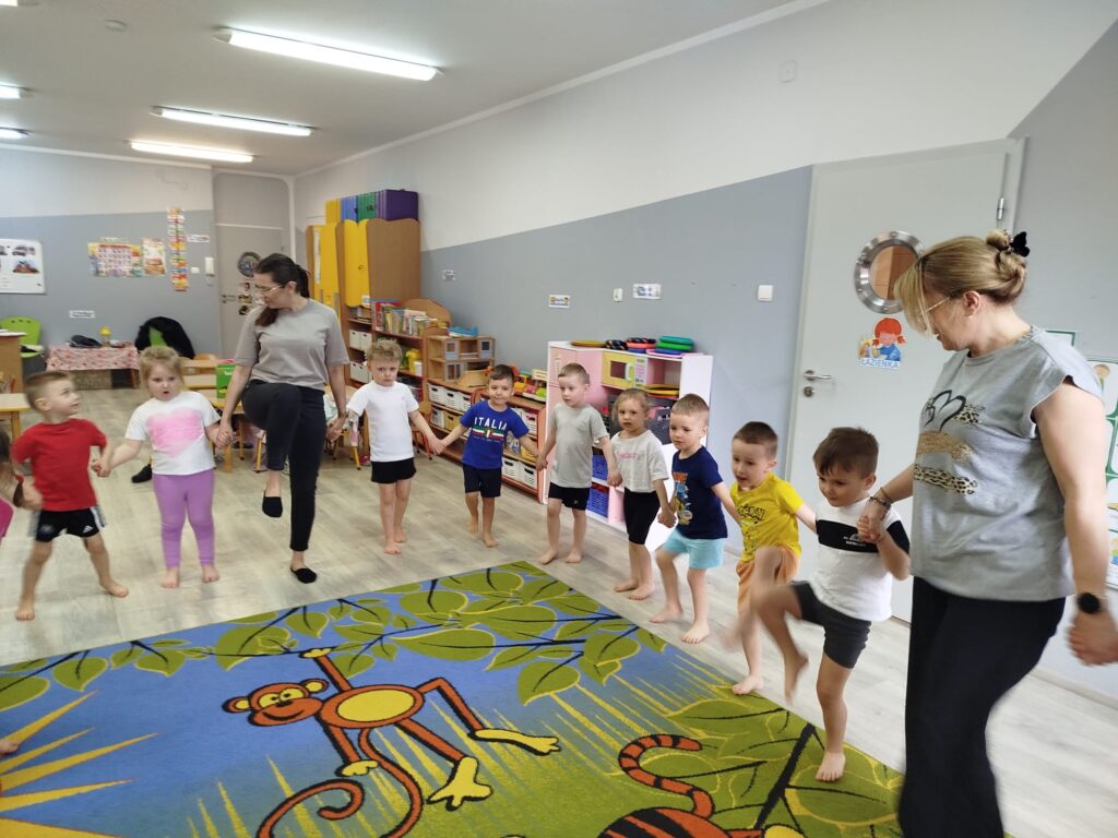 Dzieci cwicza w swojej sali na zajęciach sportowych razem z zaproszonym gościem - ternerm fitness