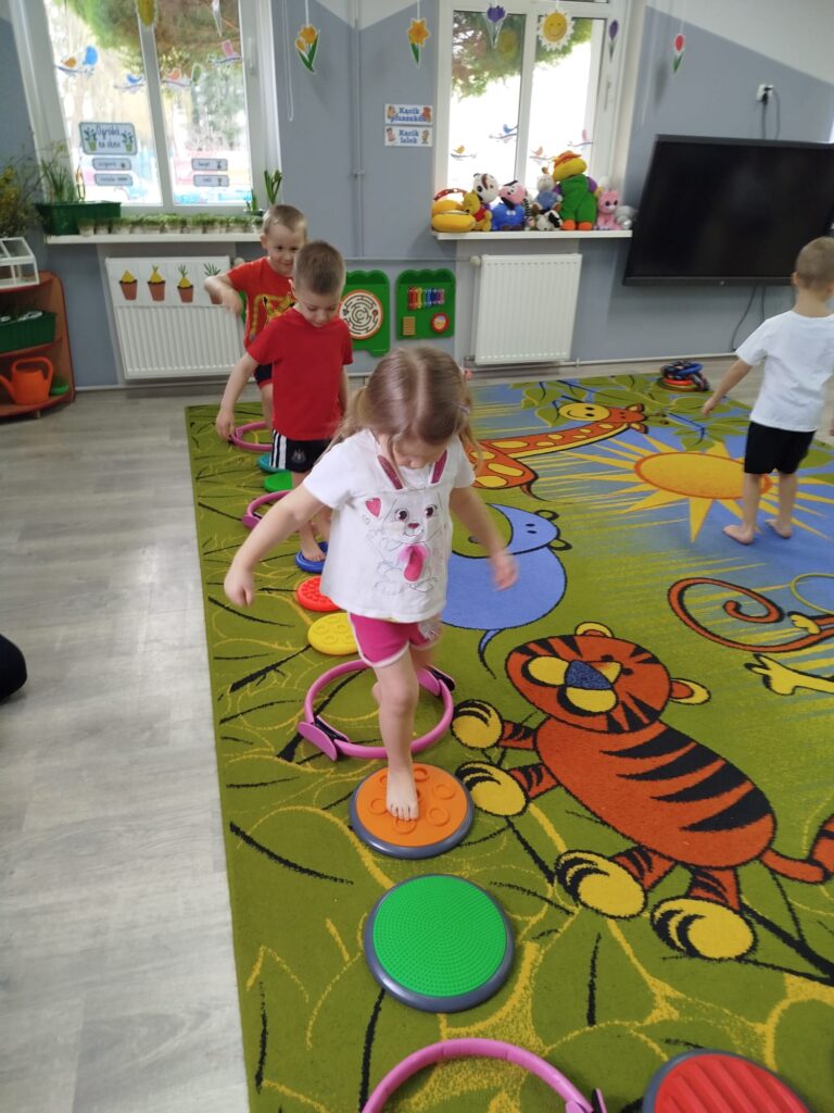 Kazdy przedszkolak pokonuje tor przeszkód zlozony z rekwizytów i przyrządów sportowych do zabaw fitness. 