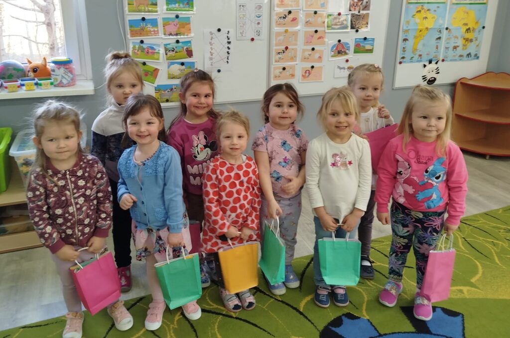 Dziewczynki obchodza swoje święto DZIEN KOBIET , Stoja przed tablica trzymają w ręku upominki ktore otrzymały od chłopaków