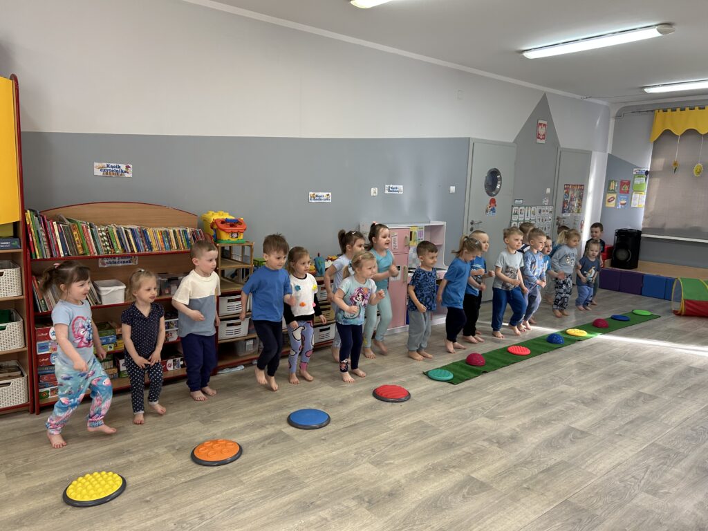 Rozgrzewka dzieci ubranych w stroje sportowe, ćwiczą przygotowując się do zawodów sportowych, w ktorych wezmą udzial. 