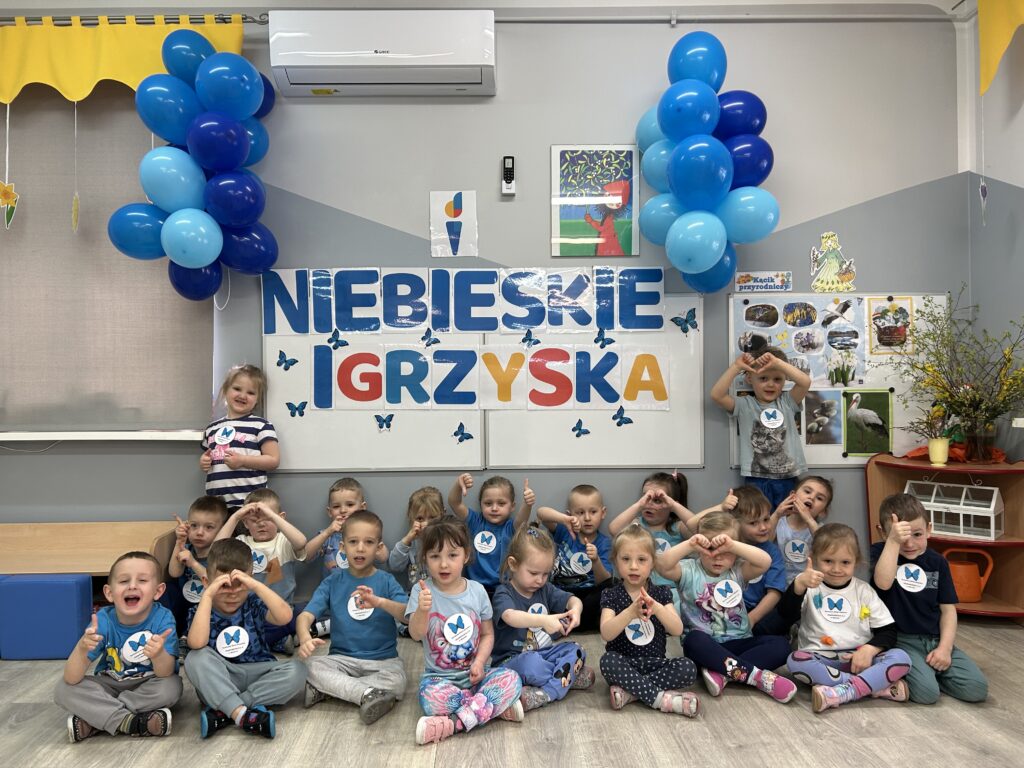 Pamiątkowe zdjęcie dzieci przed tablica z napisem NIEBIESKIE IGRZYSKA .