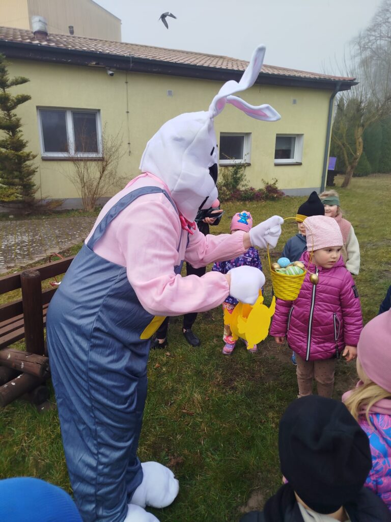 Przedszkolaki spotykaja w ogrodzie wielkanocnego zająca ktory zostawia im niespodzianki za zeebrane jajeczka