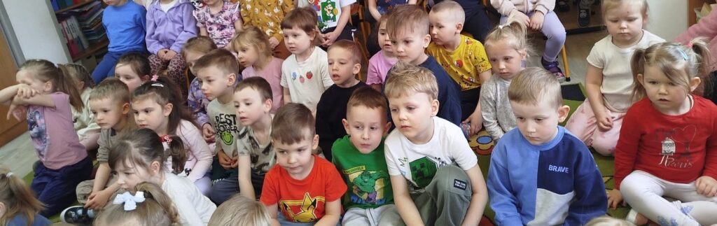 Dzieci siedza na dywania słuchaja koncertu muzyków z Filharmoanii